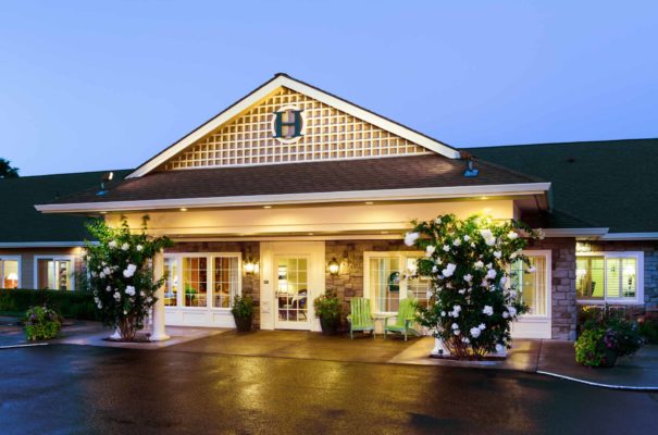 exterior view of hampton and ashley inn memory care facility in vancouver washington at sunset with white flowers on bushes