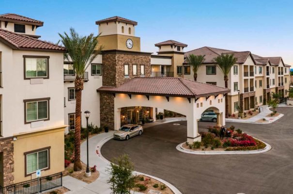 exterior daytime view of the senior apartments at the park at sunrise senior living with palm trees and bushes dotting the landscaping