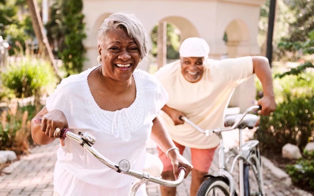 senior living couple laughing and getting ready for a bike ride at their retirement community